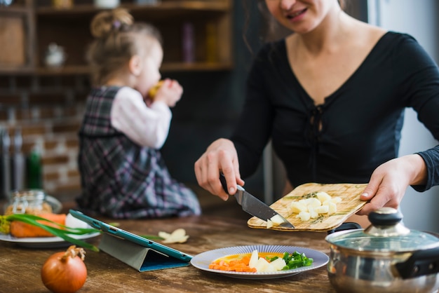 La donna di raccolto che mette la mela tagliata sul piatto