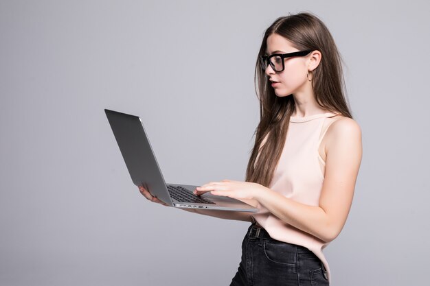 La donna di successo sta stando sopra isolato sulla parete bianca