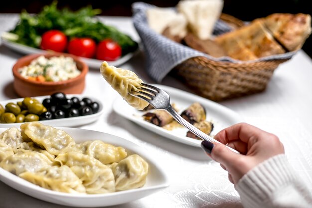 La donna di vista laterale mangia il gyurza azero tradizionale del piatto con le olive