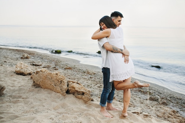 La donna e l'uomo stanno abbracciando sulla spiaggia vicino al mare