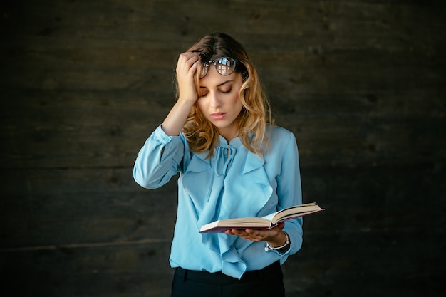 La donna esausta sembra stanca, tiene un libro, tiene la testa con la mano