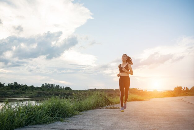 La donna felice del corridore funziona nell&#39;esercizio pareggiante del parco.