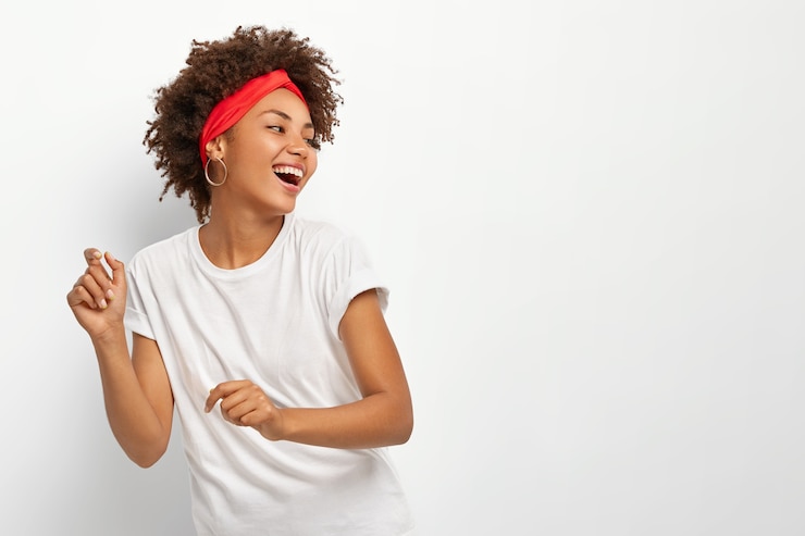 Foto gratuito la donna felice e positiva guarda volentieri lontano, balla a ritmo di musica, tiene la testa voltata, vestita con abiti casual