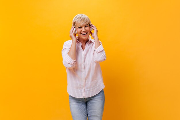 La donna felice in camicia e jeans ascolta la musica in cuffia