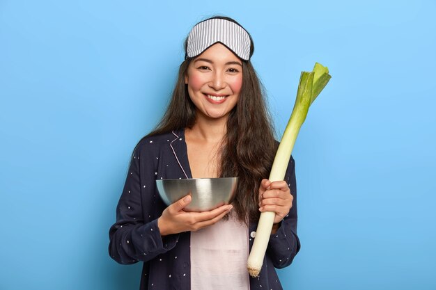 La donna felice tiene il porro verde crudo, ritorna dal mercato della drogheria