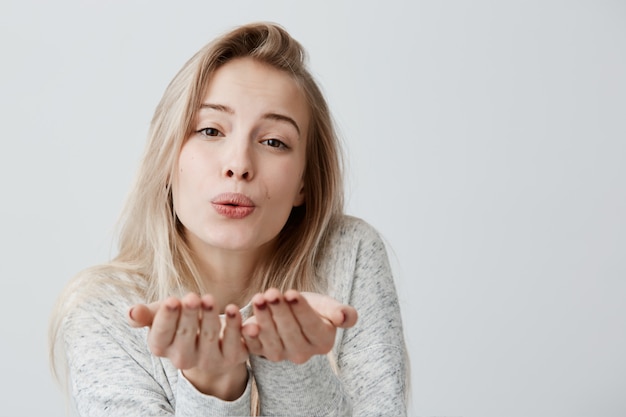 La donna femminile attraente bionda soffia il bacio