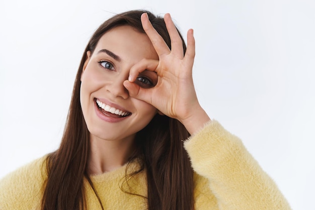 La donna femminile spensierata splendida del ritratto del primo piano che sorride esprimono le emozioni positive felici guarda attraverso la testa giusta di inclinazione di gesto non ha problemi si sentono rilassati e felici del fondo bianco