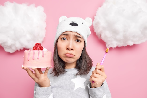 la donna ha la tentazione di mangiare una gustosa torta dolce ma ha paura di avere problemi con i denti tiene lo spazzolino da denti