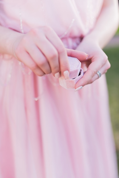 La donna in abito rosa tiene una piccola scatola regalo