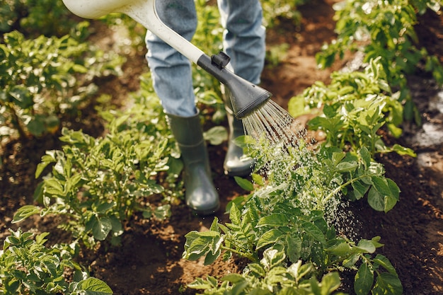 La donna in un cappello che tiene imbuto e lavora in un giardino