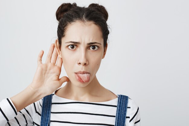 La donna incuriosita tiene la mano vicino all'orecchio, origliando