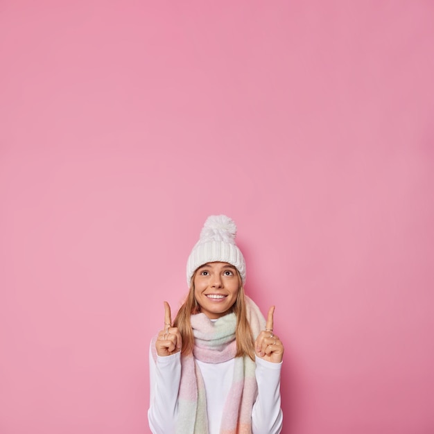 la donna indossa il cappello invernale e la sciarpa intorno al collo pone contro i punti rosa sopra allo spazio vuoto della copia