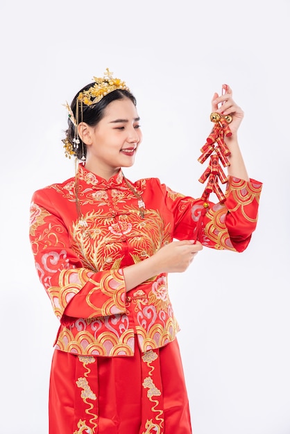 La donna indossa il sorriso del vestito cheongsam per ottenere petardi dal capo nel capodanno cinese