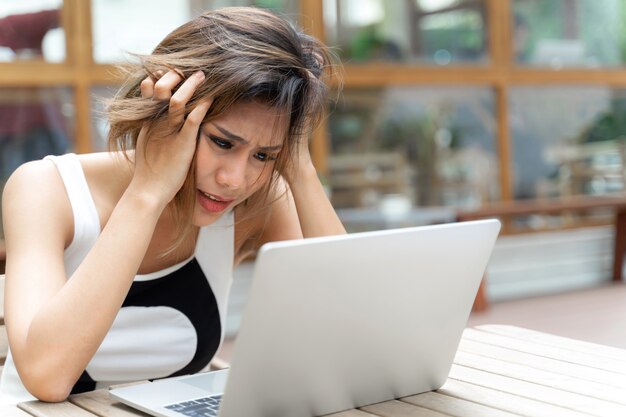 La donna lavoratrice ritiene il computer portatile serio e sembrante sulla tavola