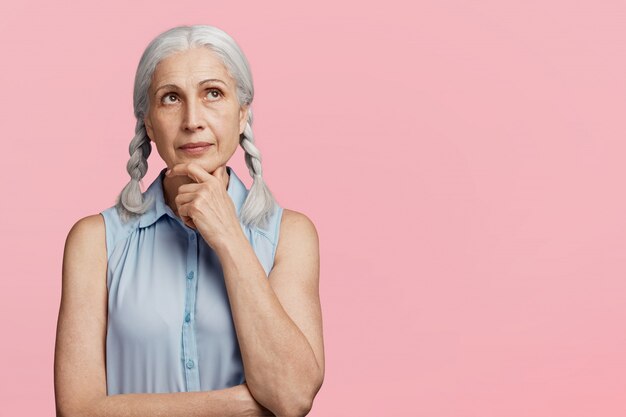 La donna maggiore con le trecce si è vestita in camicetta blu