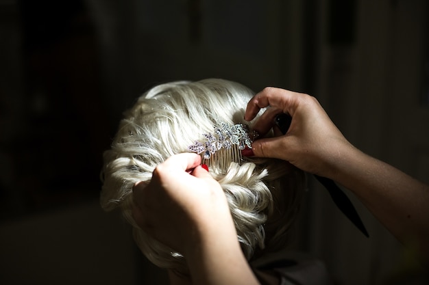 La donna mette la forcina di cristallo nei capelli biondi della sposa