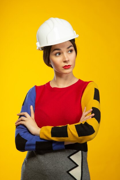 La donna nel casco della costruzione posa sulla macchina fotografica