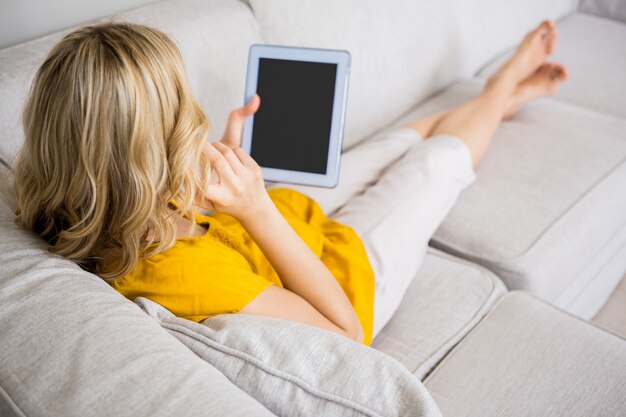 La donna parla al cellulare mentre si utilizza tavoletta digitale in salotto