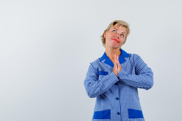 La donna pensante sta stringendo le mani sul petto su sfondo bianco