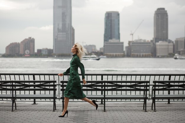 La donna premurosa funziona nel suo vestito elegante lungo la riva del fiume a New York