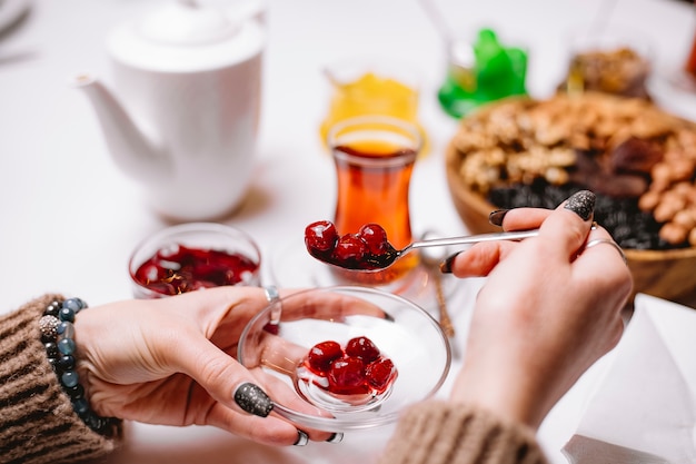 La donna prende il tè della marmellata di amarene nella vista laterale armudy