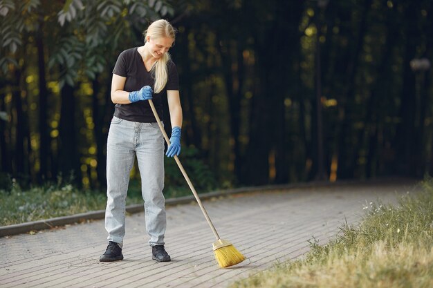 La donna raccoglie le foglie e pulisce il parco