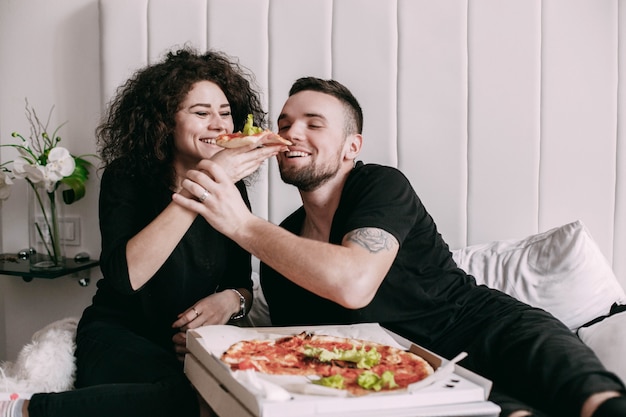 La donna riccia dà un pezzo di pizza al suo uomo