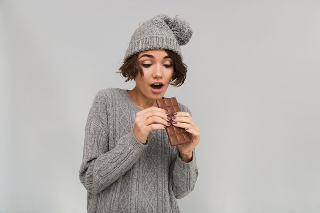 La donna scossa si è vestita in maglione e cappello caldo che tengono il cioccolato.