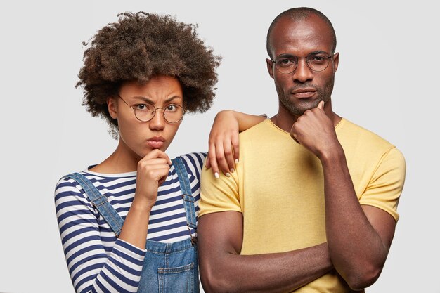 La donna seria e l'amico dell'uomo tengono i menti, concentrati sulla fotocamera, hanno espressioni dispiaciute