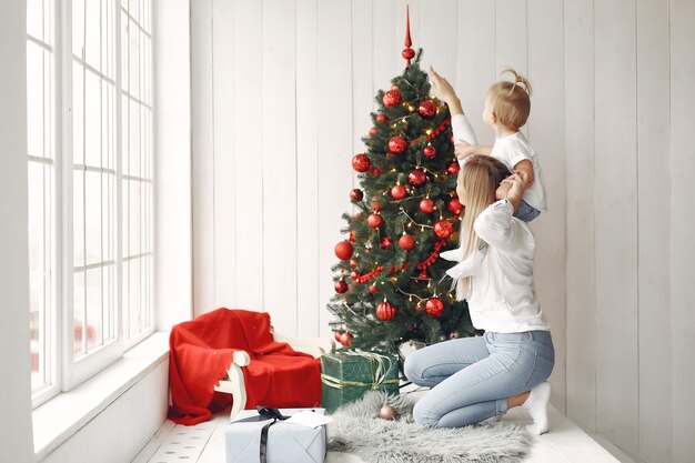La donna si diverte a prepararsi per il Natale. La madre in una camicia bianca sta giocando con sua figlia. La famiglia sta riposando in una stanza festiva.