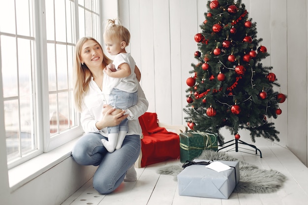 La donna si diverte a prepararsi per il Natale. La madre in una camicia bianca sta giocando con sua figlia. La famiglia sta riposando in una stanza festiva.