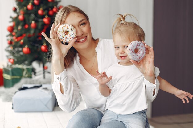 La donna si diverte a prepararsi per il Natale. La madre in una camicia bianca sta giocando con sua figlia. La famiglia sta riposando in una stanza festiva.