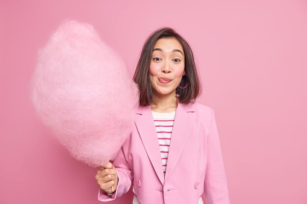 la donna si lecca le labbra mentre tiene un dolce appetitoso zucchero filato vestito con abiti formali alla moda