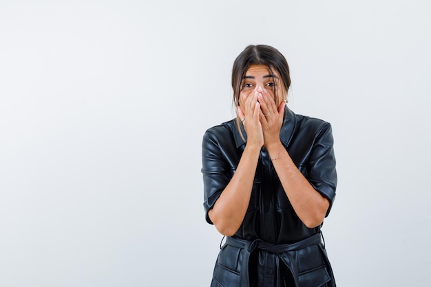 La donna sorprende coprendosi la bocca con le mani su sfondo bianco