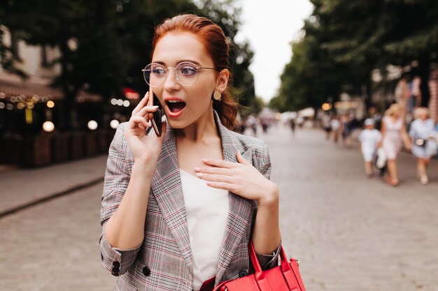 La donna sorpresa in occhiali esamina la macchina fotografica