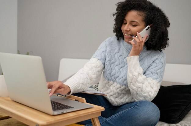 La donna sorridente del tiro medio parla al telefono