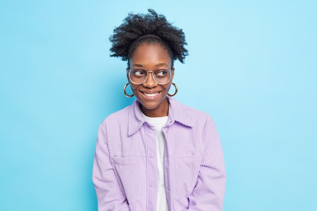 La donna sorridente felice con i capelli ricci della pelle scura distoglie lo sguardo essendo di buon umore