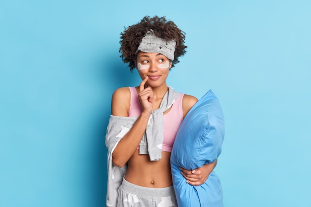 La donna sorridente sognante con i capelli ricci si prepara per dormire