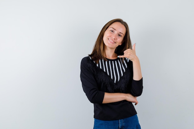 La donna sorridente sta mostrando il gesto del telefono cellulare con la mano su sfondo bianco