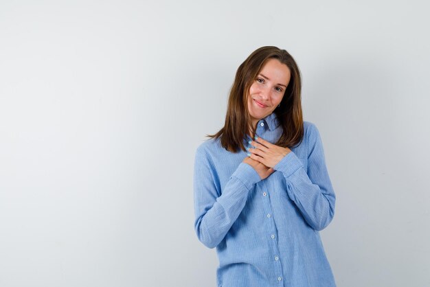 La donna sorridente sta stringendo le mani sul petto su sfondo bianco