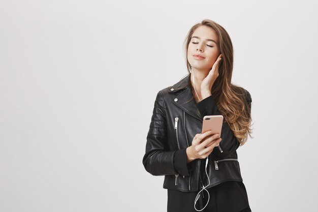 La donna spensierata chiude gli occhi e sorride come musica d'ascolto in cuffie, tiene il telefono cellulare