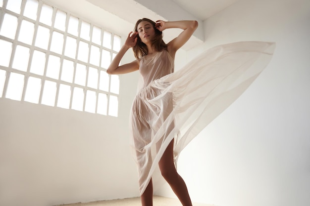 La donna sta ballando in abito da ballerina in loft leggero con finestra industriale