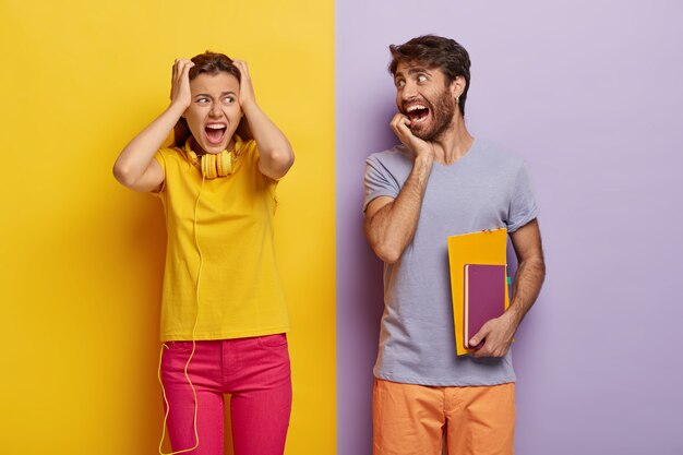 La donna stressante tiene le mani sulla testa, è in preda al panico, urla forte, vestita con abiti gialli e rosa, l'uomo divertente guarda felice il compagno di gruppo, porta il diario, ha una scadenza per prepararsi all'esame