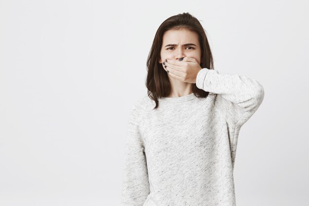 La donna sveglia del brunette si copre la bocca ed esprime disgusto o antipatia