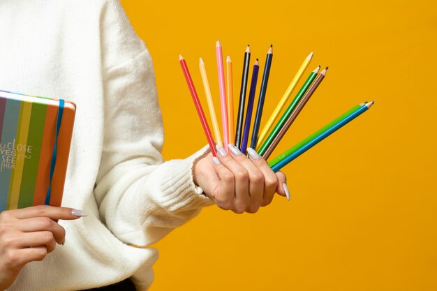 La donna tiene matite colorate e blocco note colorato
