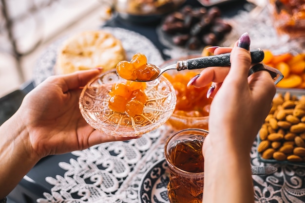 La donna tiene una casseruola di cristallo con marmellata di amarene e cucchiaino