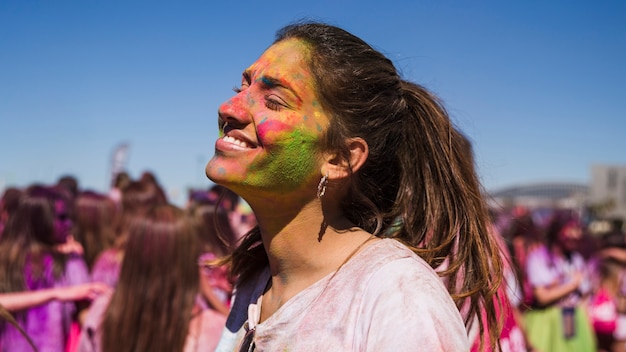 La faccia sorridente della giovane donna ha dipinto con il colore di holi