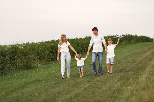 La famiglia cammina in un campo e gioca con l'aereo giocattolo