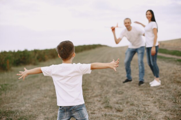 La famiglia cammina in un campo e gioca con l'aereo giocattolo