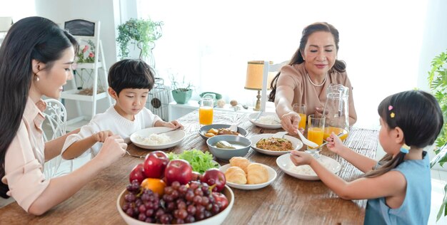 La famiglia felice asiatica trascorre del tempo pranzando sul tavolo insieme relazione e attività in casa